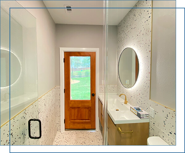 Bright bathroom with a wooden door and oval mirror.